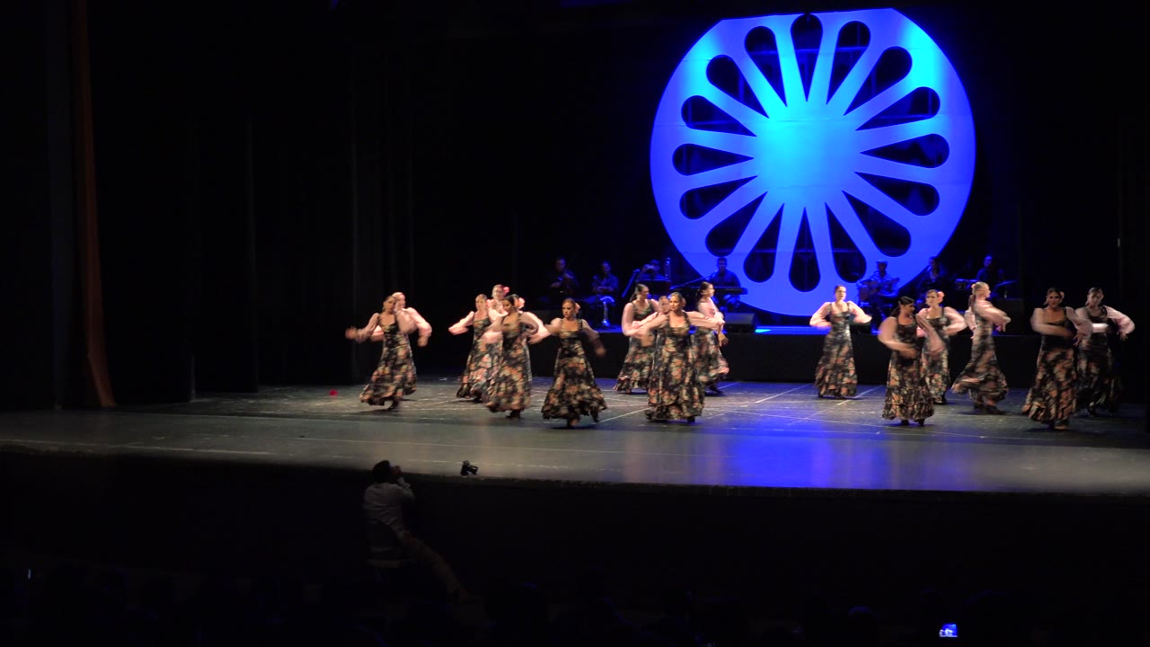 Women dancers shift toward the right side of the stage.