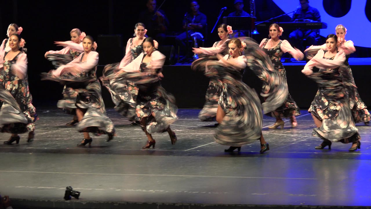 Dancers turning with skirts flaring on stage.