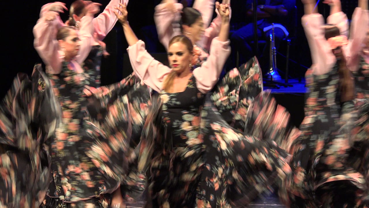 Women in floral dresses dancing on a dark stage