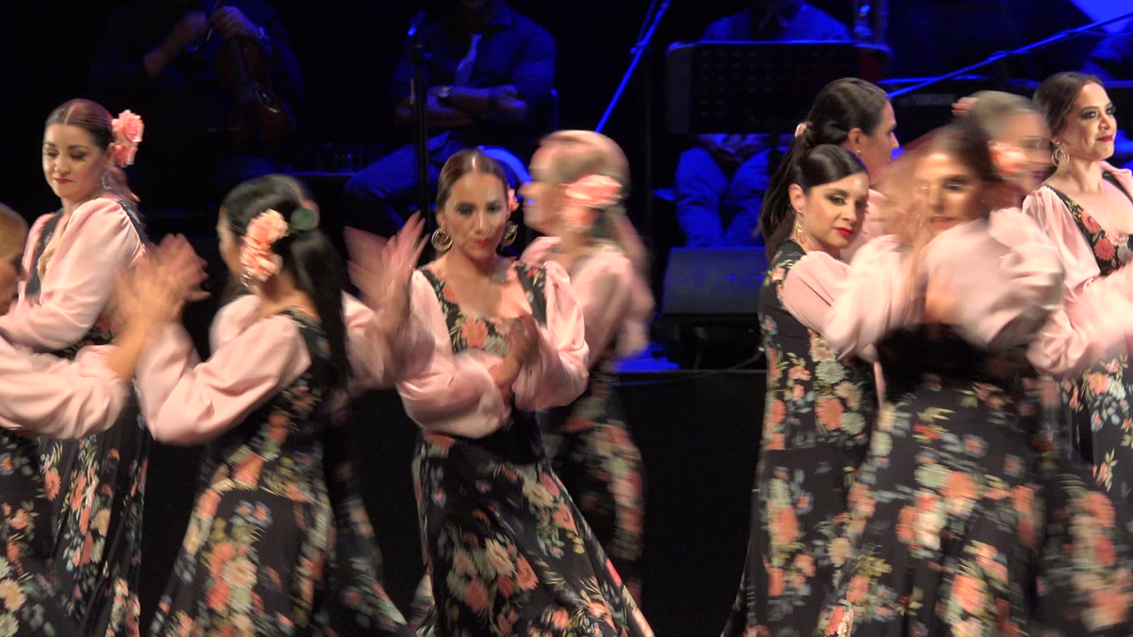 A second early frame shows the Cabo San Lucas stage performance with one dancer blurred in the foreground and other women in coordinated floral costumes behind her.