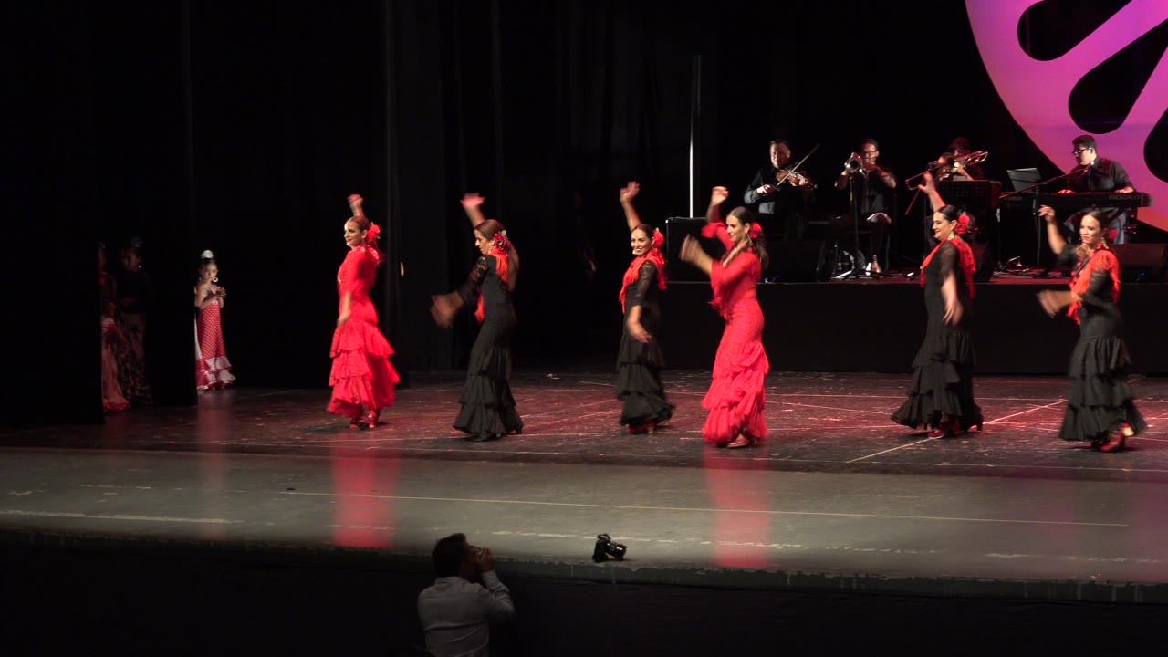 A wide Cabo San Lucas stage view shows the dancers shifting positions with raised arms while the musician platform stays centered in the background.
