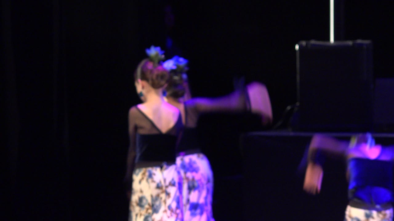 Child dancer in black top on a dark stage with purple light