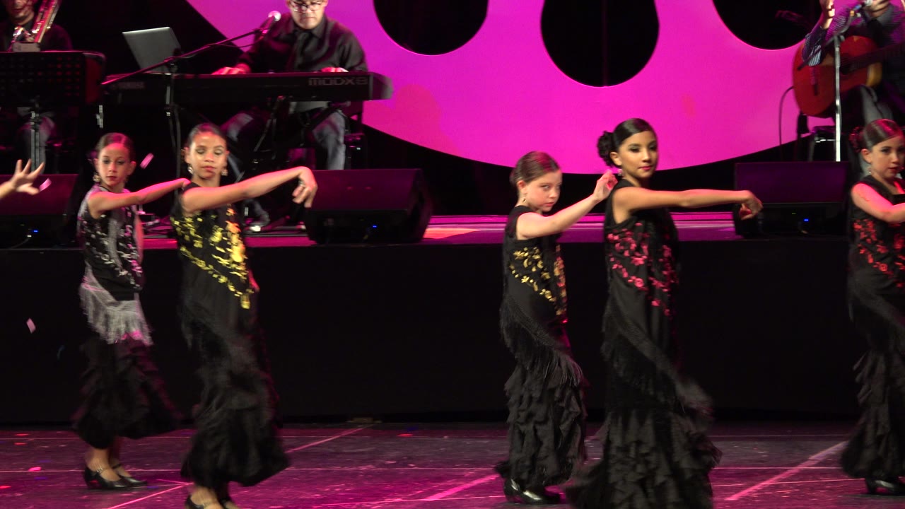 Three young dancers face forward during a stage routine.