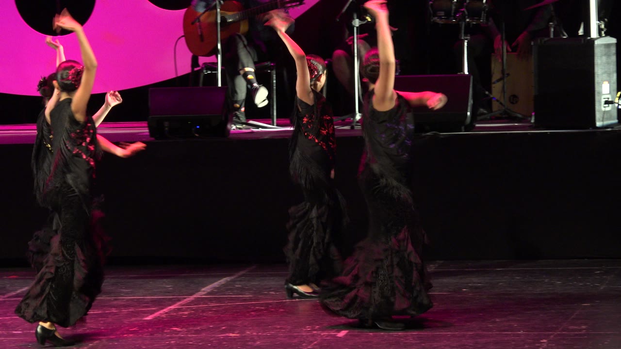 Dancers in black costumes on a pink-lit stage.