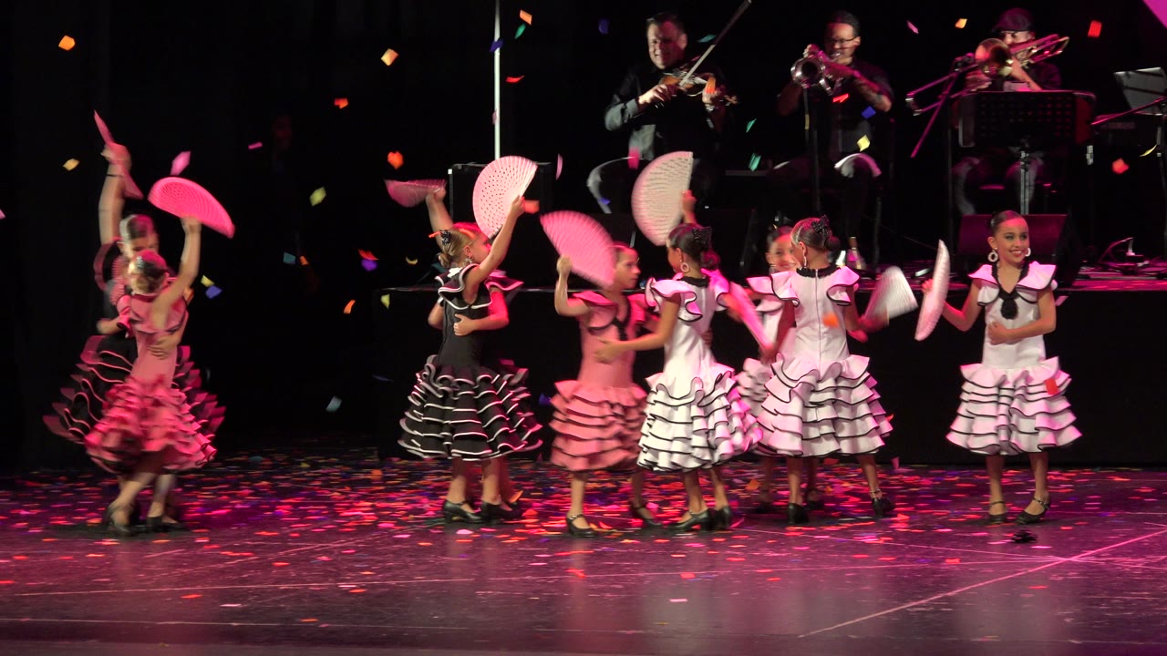 Children hold fans high during a stage dance number.