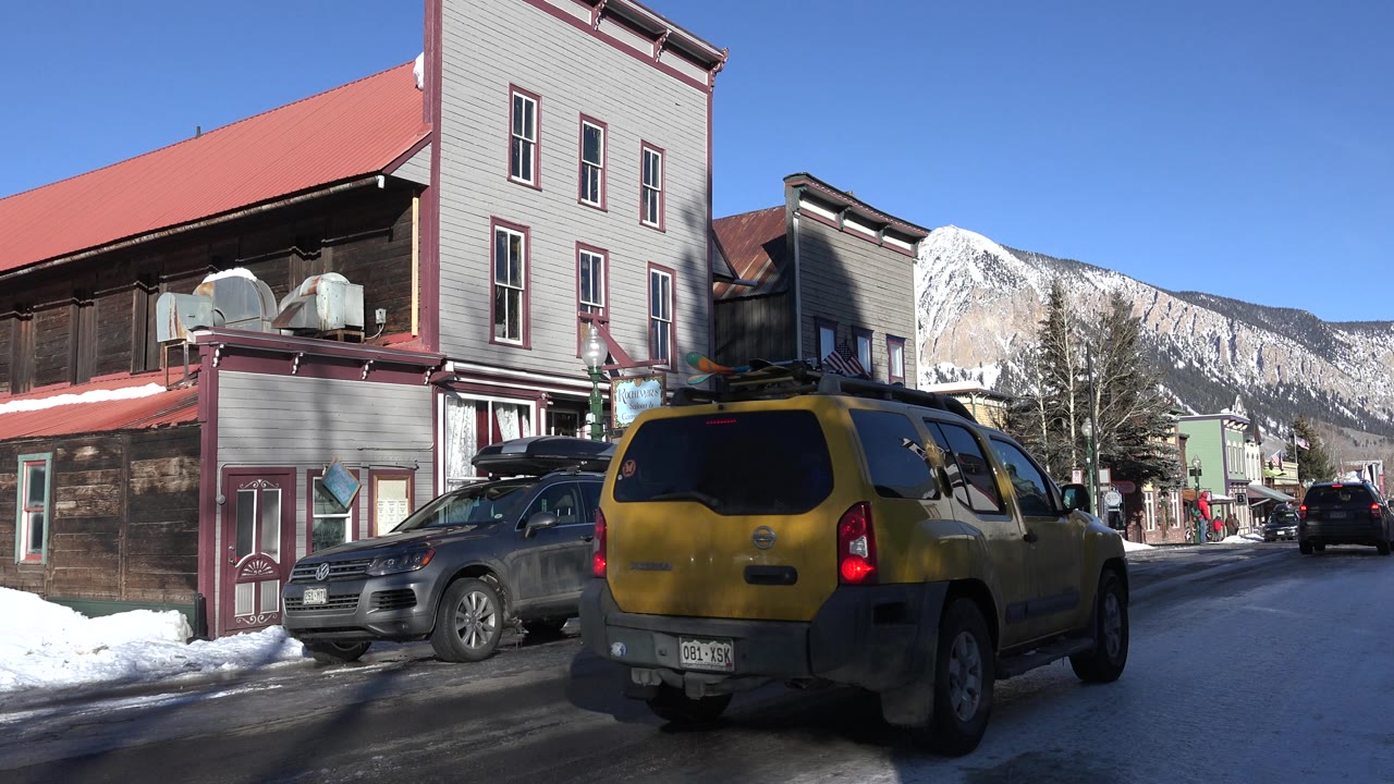 Yellow SUV farther down snowy street near parked crossover
