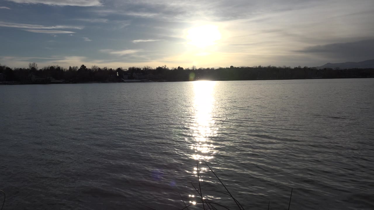 Sunset reflection on lake with distant hills and clouds