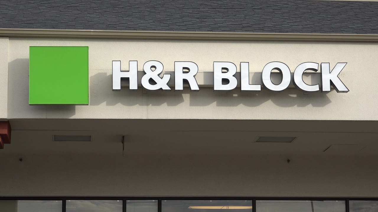 One second in, the white H&R Block letters remain prominent beside the green logo on the Westminster storefront, with the facade shadow visible and no visible people.