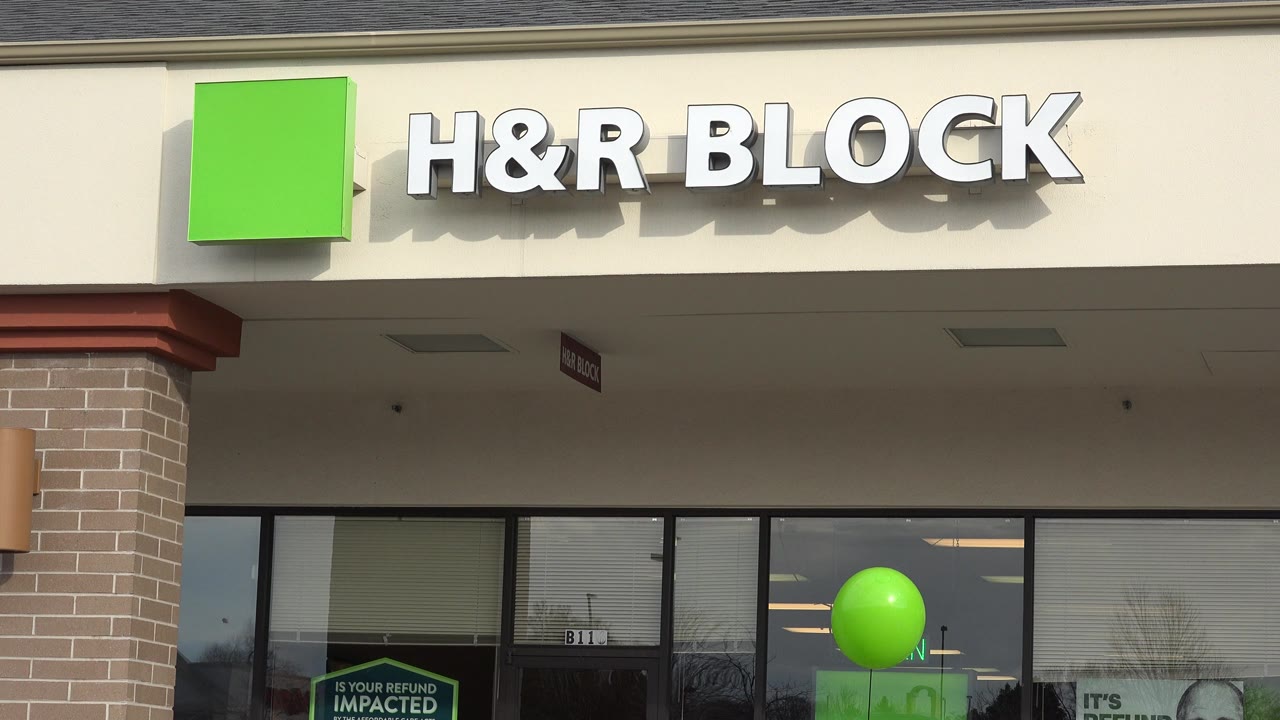 H&R Block storefront in Westminster, Colorado, with beige facade, brick column, glass windows, tax-season posters, and a green balloon near the center-right window area, with no visible people.