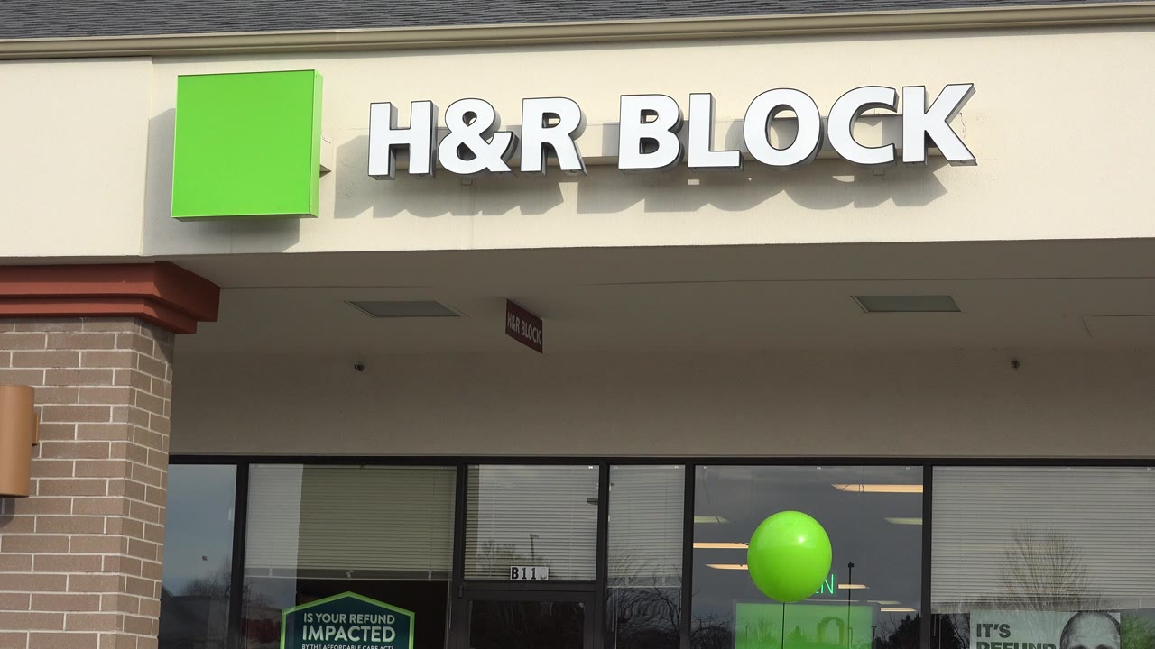A slightly tighter storefront view in Westminster, Colorado, centers the H&R Block sign above dark glass doors and windows, with a green balloon visible inside the window line and no visible people.