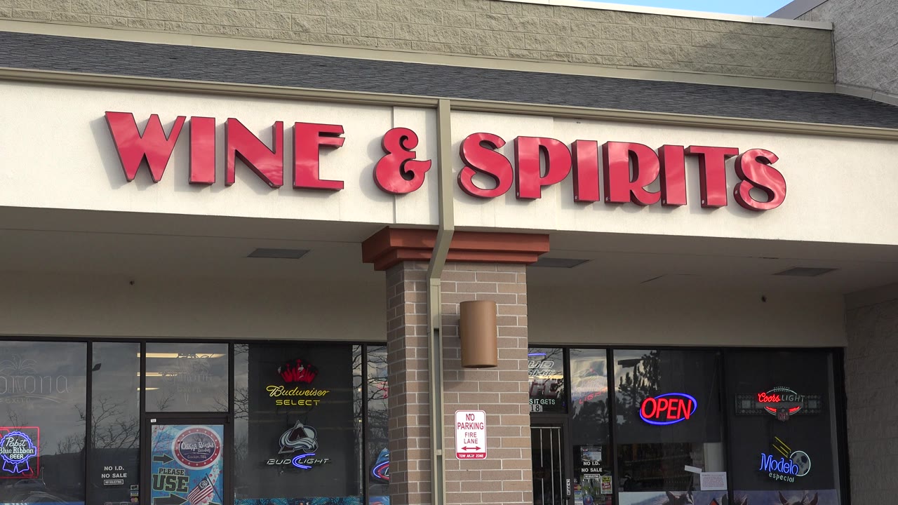Westminster, Colorado wine and spirits storefront with red sign letters, beer window decals, brick columns, and no visible people at the start of the clip.