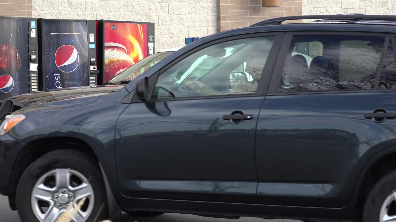 Dark SUV fills the foreground with a police car behind it.