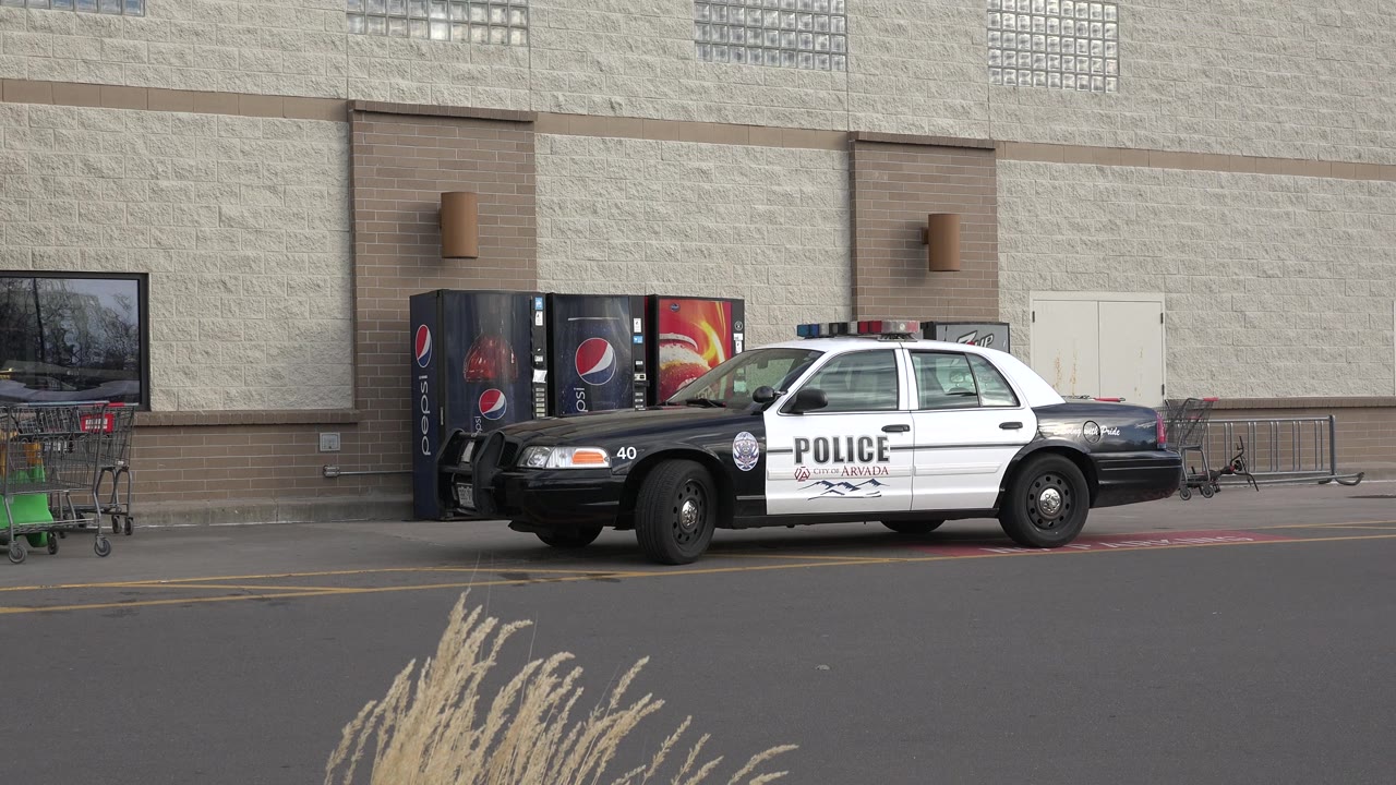 Police cruiser near shopping carts and vending machines.