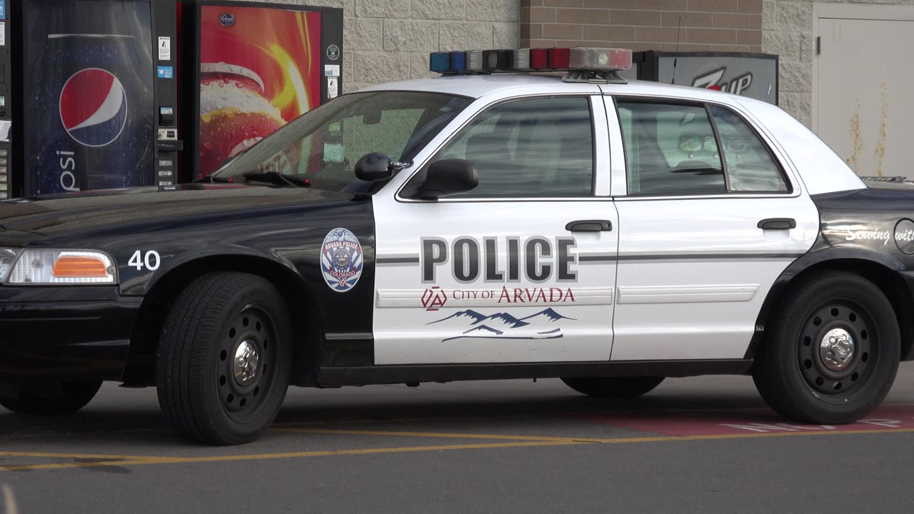 A close profile view shows a City of Arvada police car parked beside Pepsi vending machines in Westminster, Colorado, with no visible people in this frame.