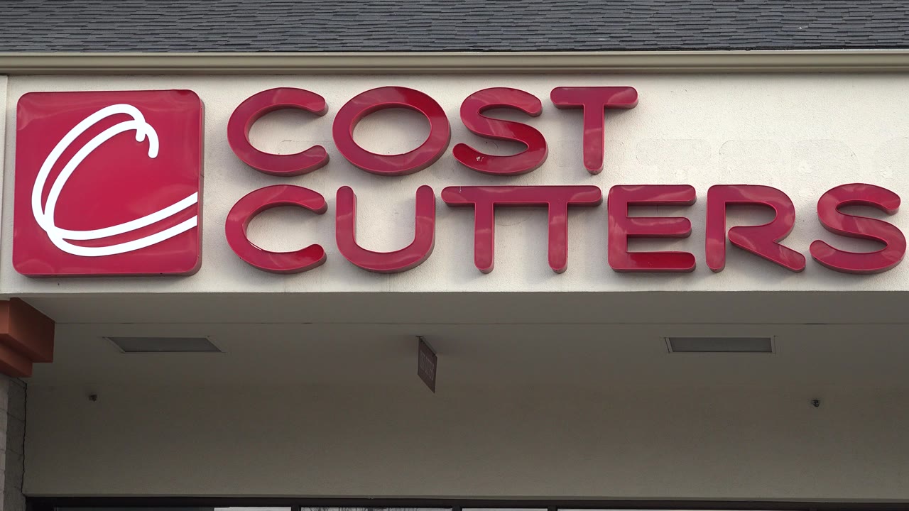 Tight view of red Cost Cutters sign on beige storefront