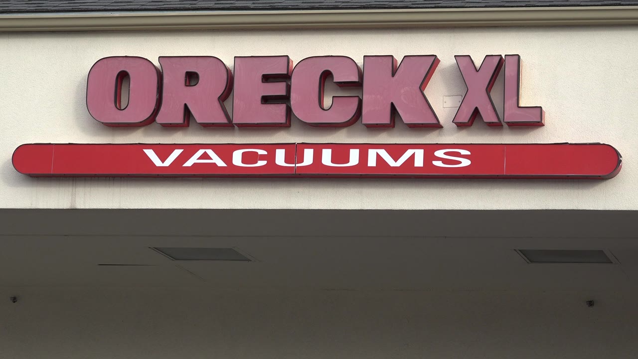 Second frame holds on the Oreck XL Vacuums lettering across the Westminster, Colorado facade, with the awning shadow cutting across the lower portion and no visible people.