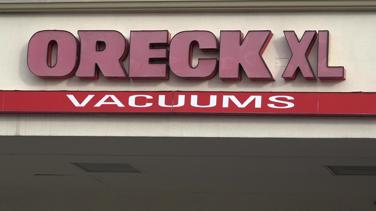 Opening frame of the Oreck XL Vacuums sign on a Westminster, Colorado building exterior, with red lettering and no visible people.