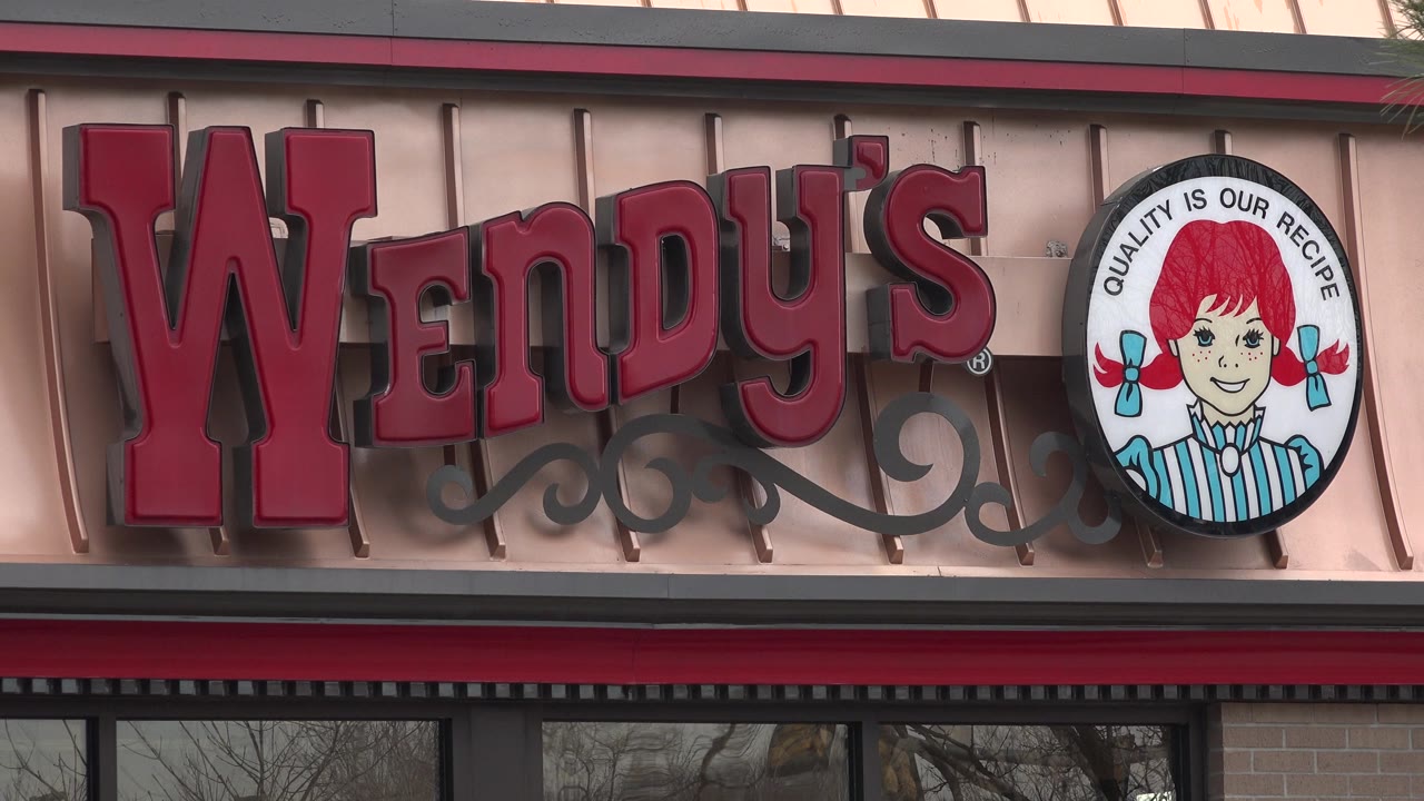 The Wendy's letters and circular logo fill the frame on a light metal restaurant facade in Westminster, Colorado, with window glass visible along the bottom and no visible people.