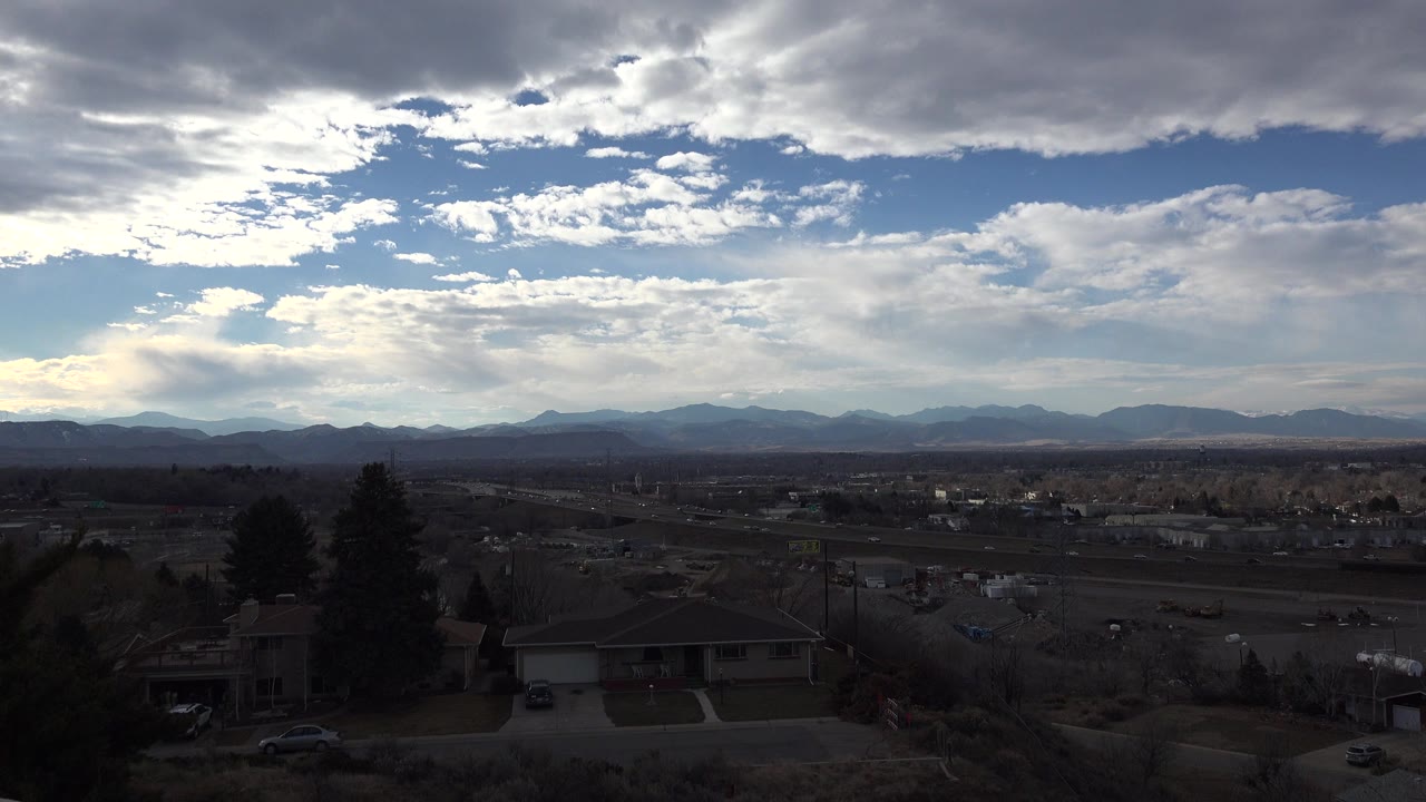 Wide suburban view under layered clouds and blue sky.