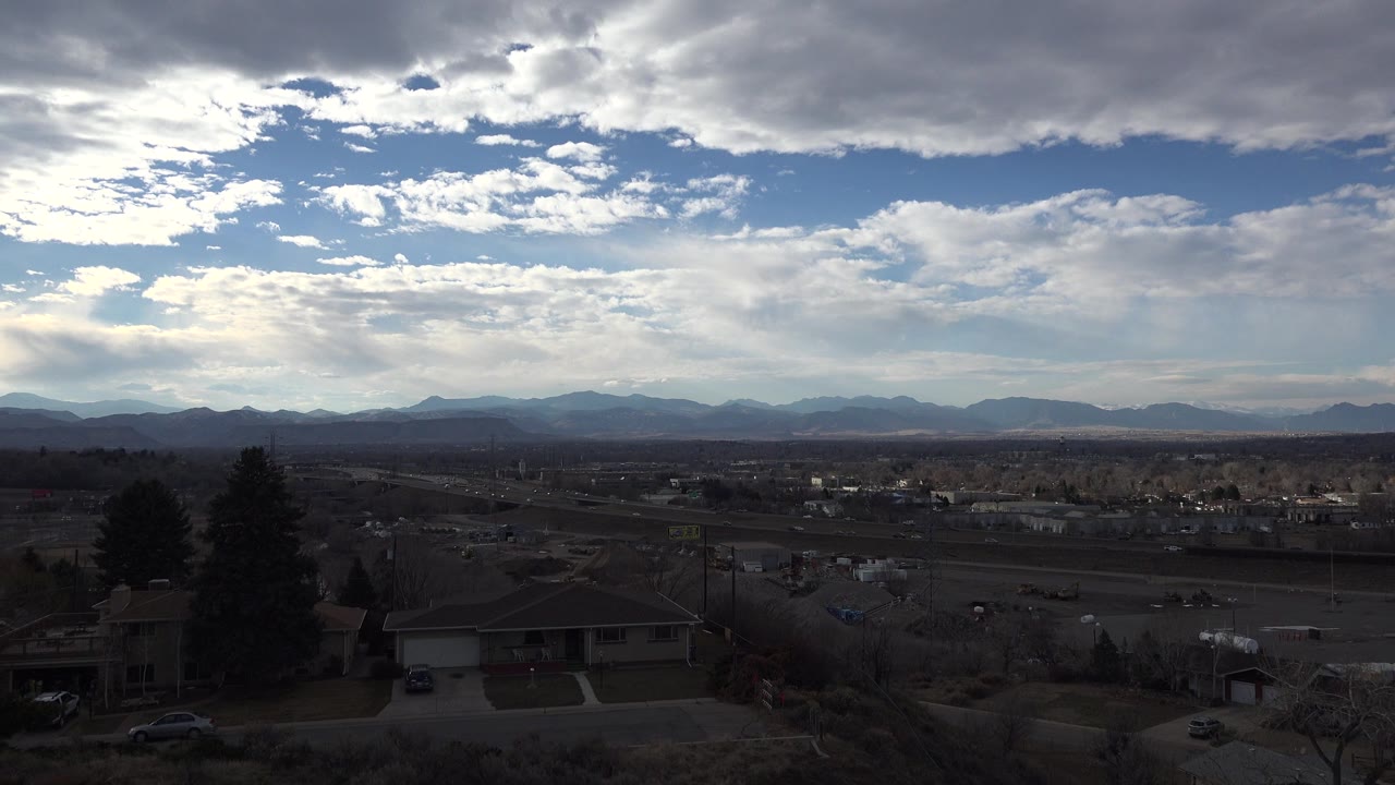 Wide town horizon with mountains under broken clouds