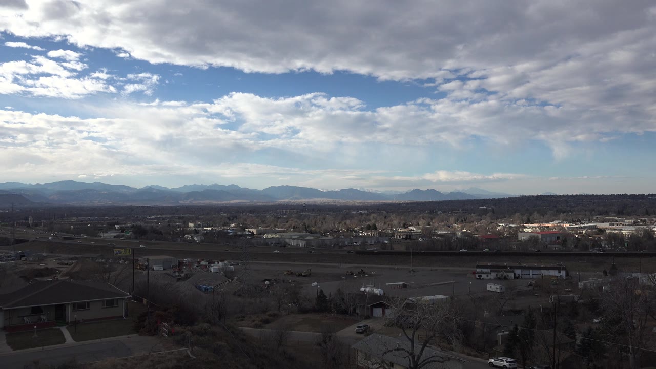 Wide view over houses toward distant mountains under a cloudy sky