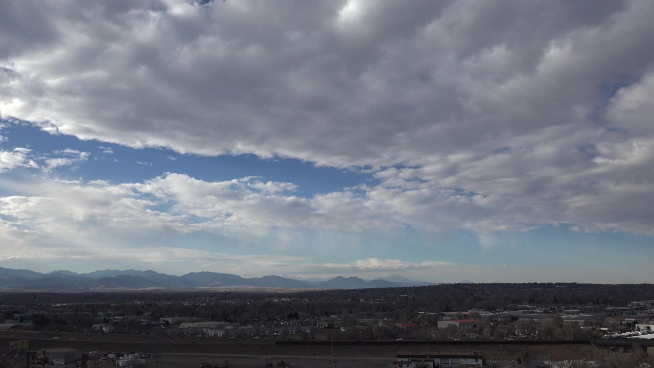 Wide suburban horizon under thick gray clouds and blue sky.