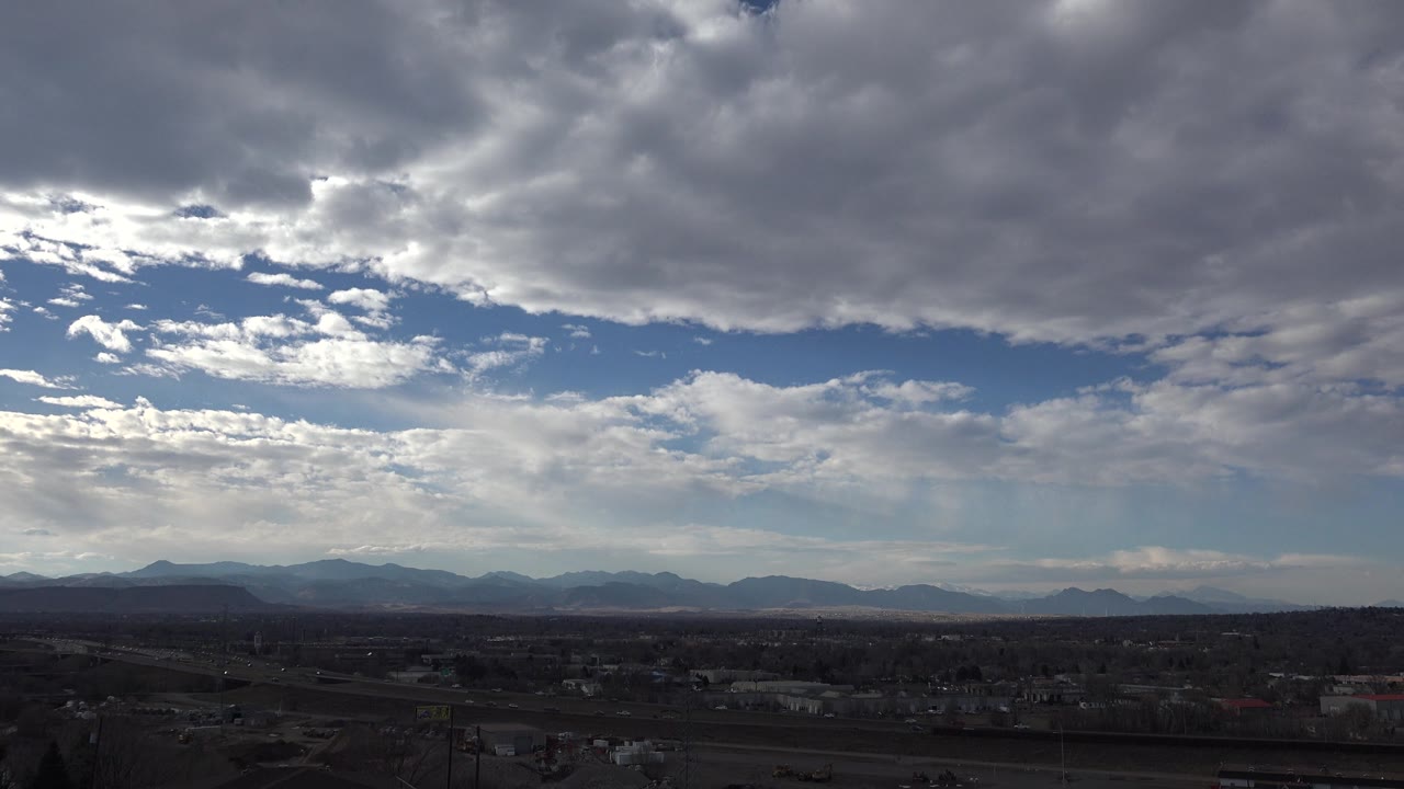 Cloudy sky over distant mountain ridge and shadowed town foreground.