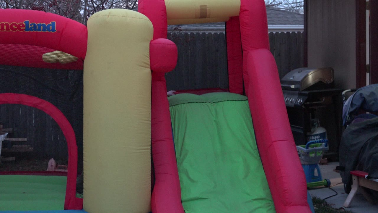Colorful inflatable play structure in a fenced backyard.