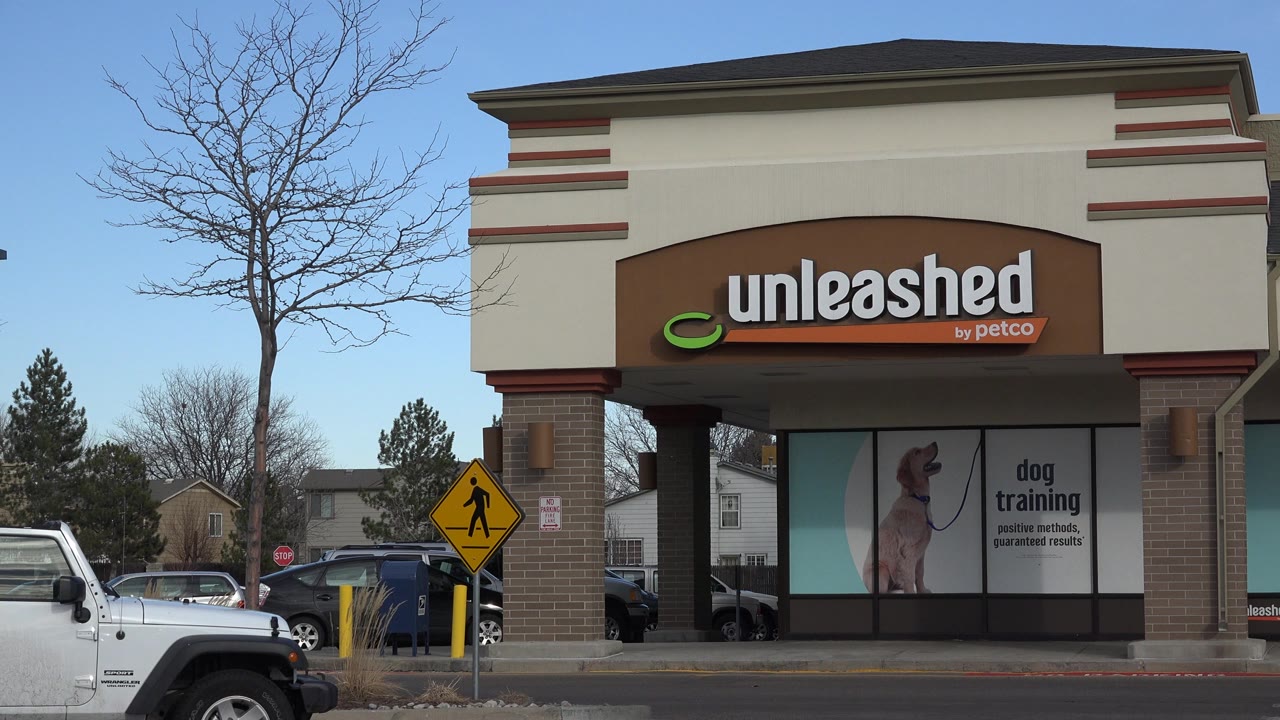 Unleashed by Petco storefront with parked vehicle and pedestrian sign.
