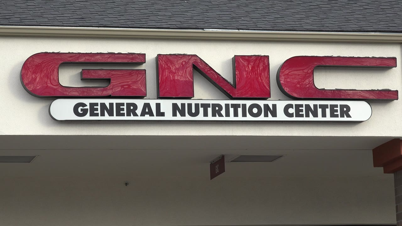 Second frame holds on the GNC General Nutrition Center sign in Westminster, Colorado, with the dark overhang below and no visible people.
