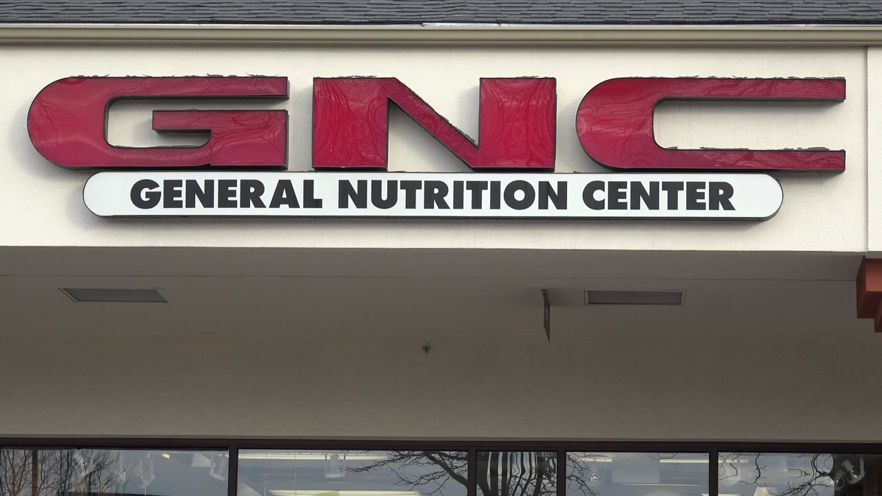 Red GNC storefront sign above dark windows.