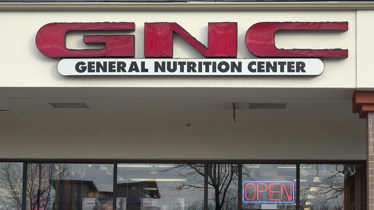 A steady view of the GNC storefront in Westminster, Colorado, shows the red brand letters, the General Nutrition Center panel, and the open sign in the right window, no visible people in this frame.