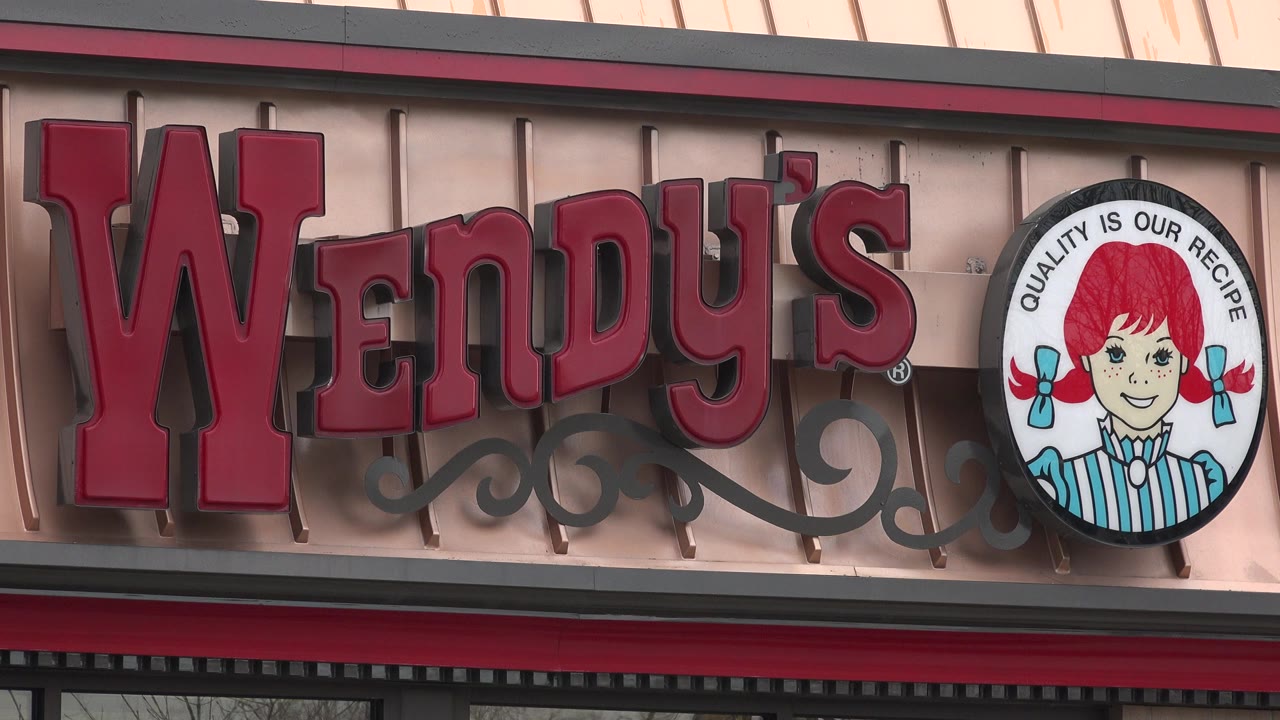 Close view of a Wendy's restaurant sign on a facade.