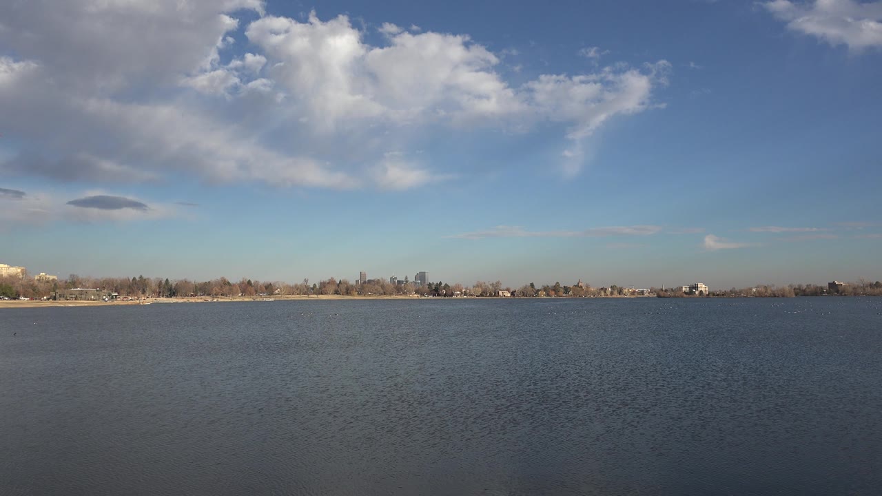 Open water with low skyline beneath a blue cloudy sky