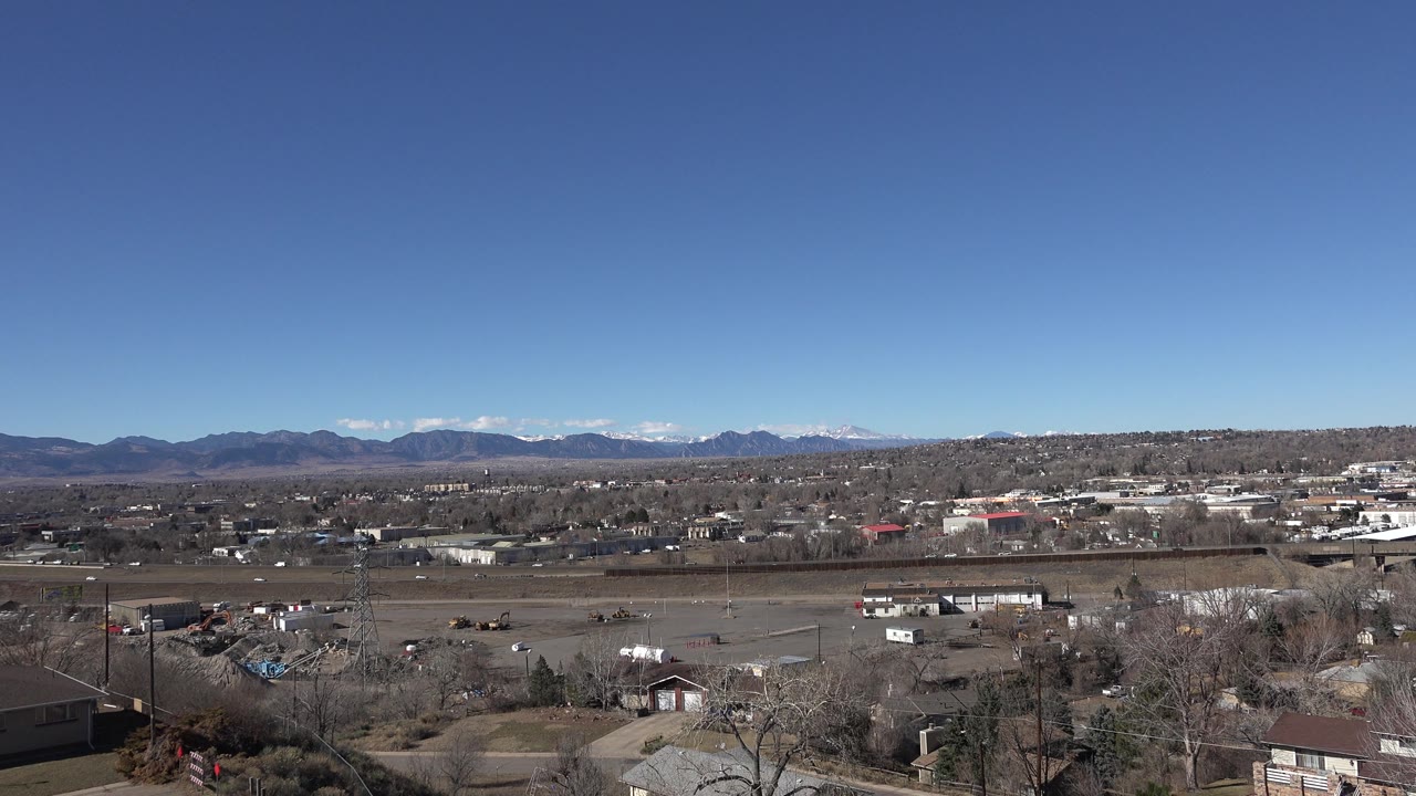 Wide landscape with town buildings, bare trees, and mountain backdrop