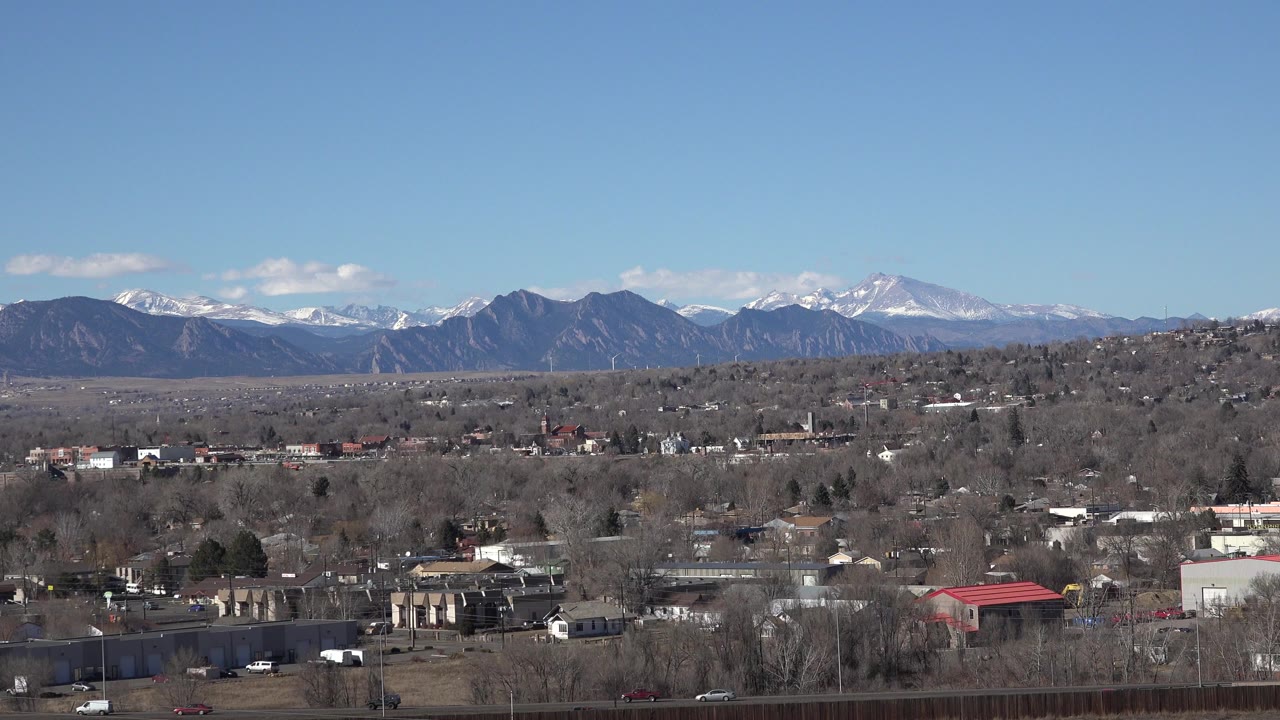 Suburban buildings and roads below distant snow-capped mountains