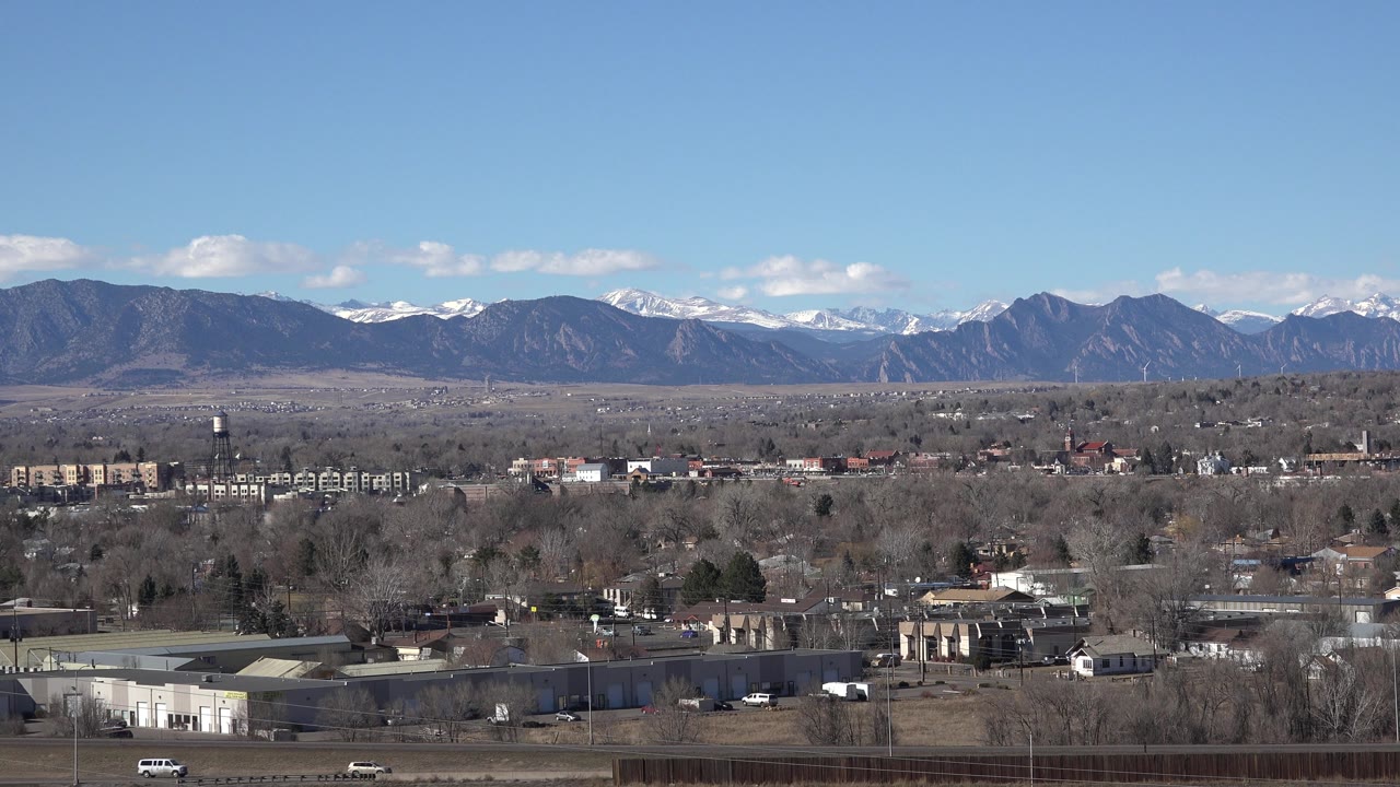 Town edge with road, trees, and mountains beyond