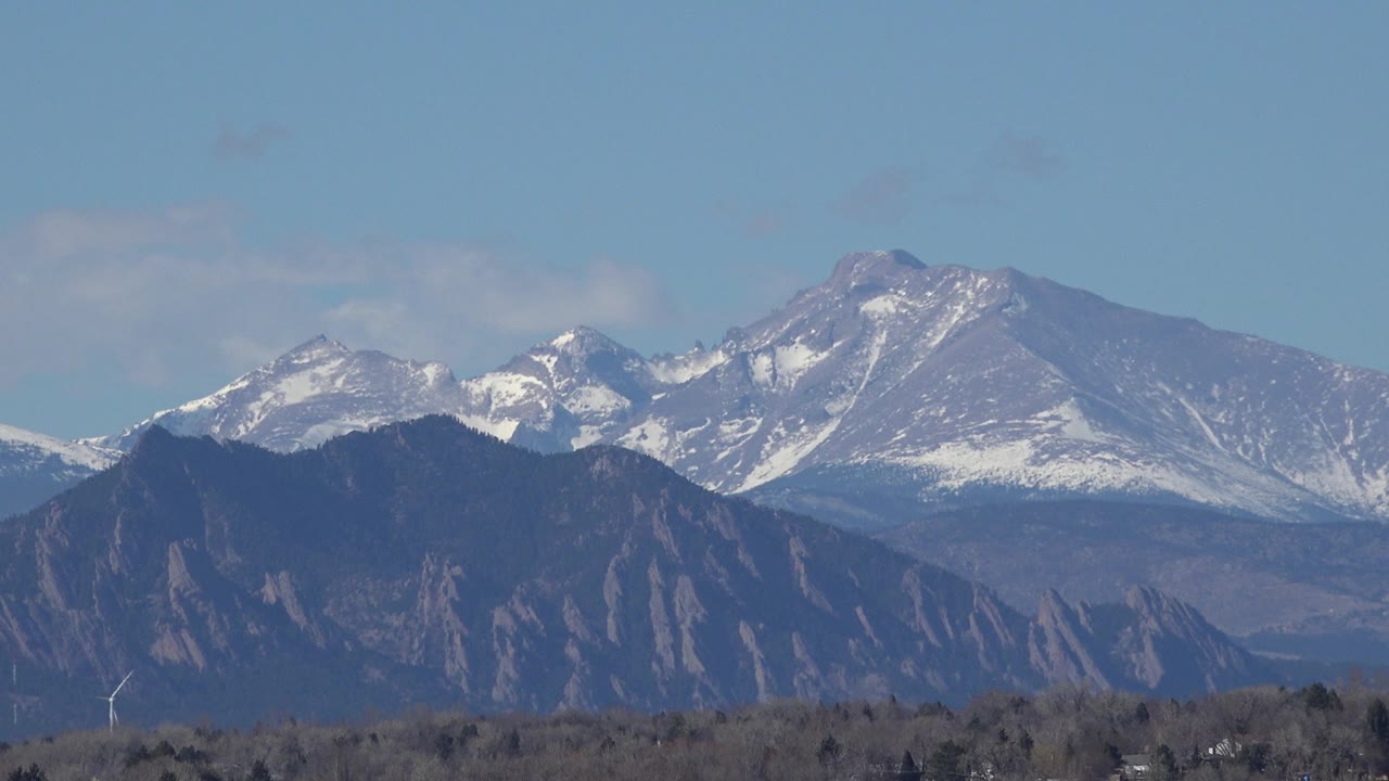 A second Westminster, Colorado frame holds the same distant snowy peaks and dark rocky ridge, with light haze softening the slopes and no visible people.