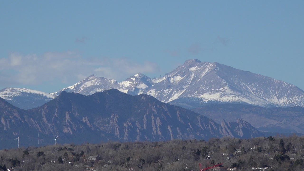 Second view of Westminster, Colorado with the main snow-dusted peak centered above foothills, distant trees, buildings, and no visible people.
