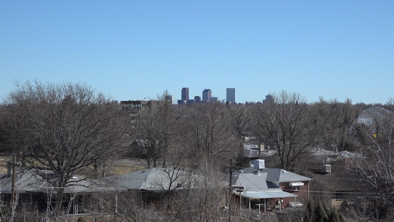 Suburban rooftops and leafless trees with a distant skyline.