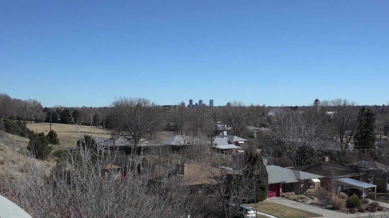 Suburban homes and winter trees under a clear blue sky.