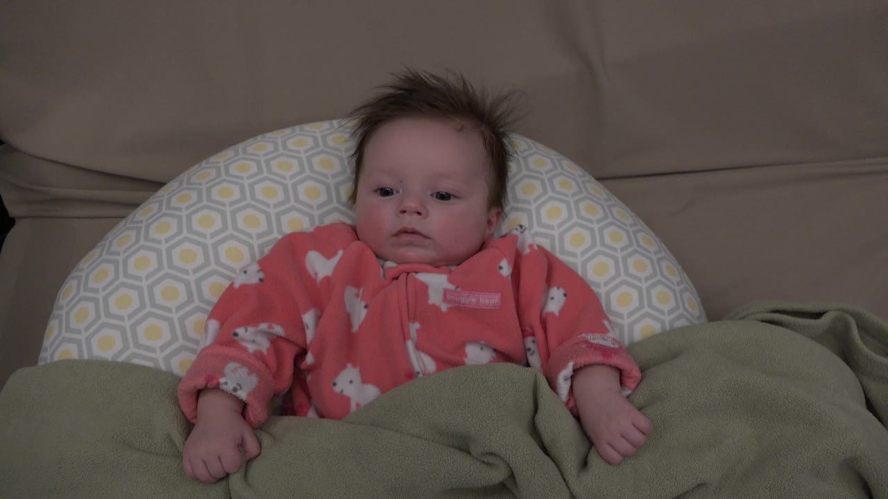 Baby looking forward from a cushioned couch setup.