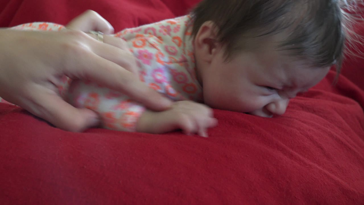 Child in floral pajamas pressed against a red cushion.