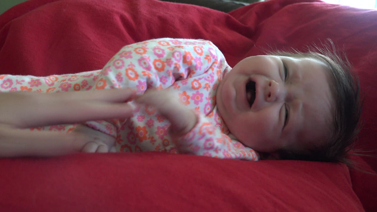 Young child lying on a red couch with mouth open.