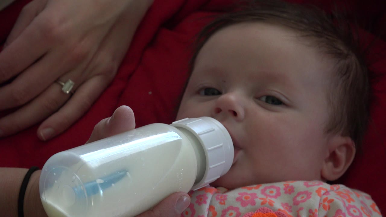 Baby drinking from a milk bottle on red cloth