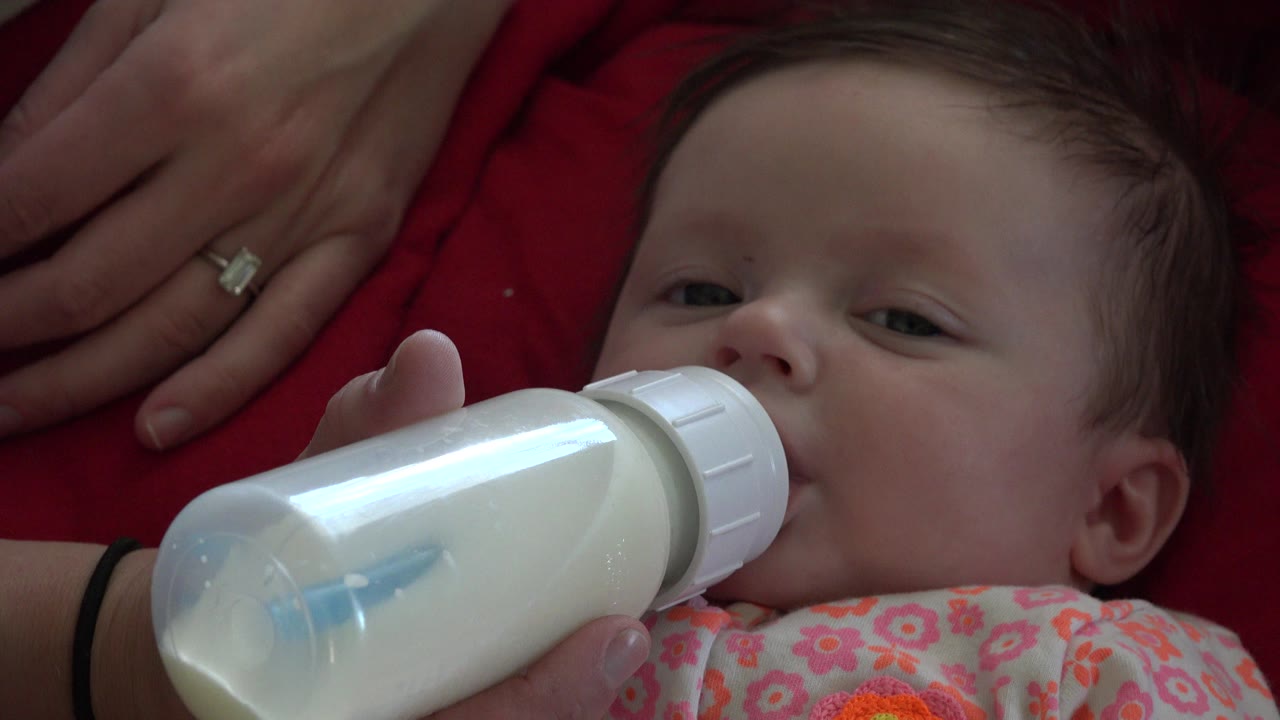 At 0:01 in Westminster, Colorado, the infant's eyes face the camera while the white bottle covers the lower part of the face.
