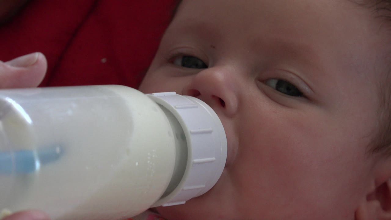 At 0:01, the bottle remains pressed to the newborn's mouth in a close Westminster, Colorado feeding shot, with the infant's eye looking toward camera.