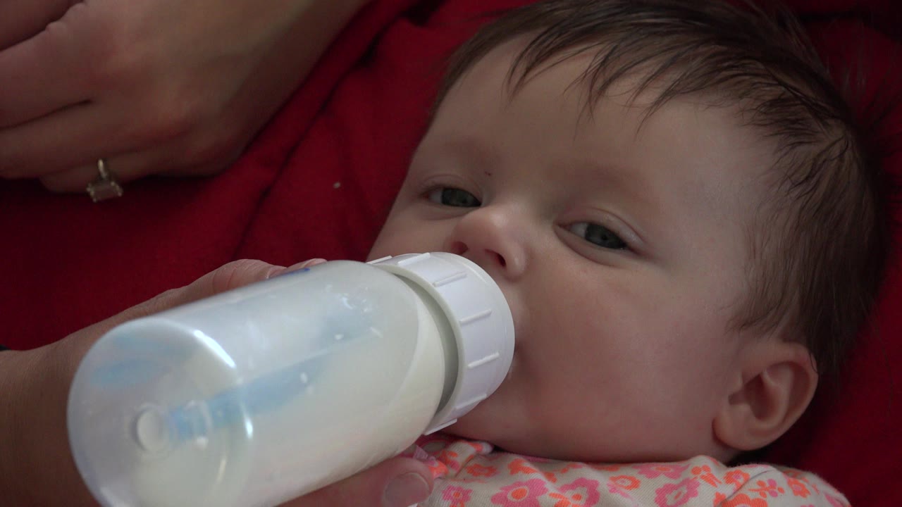 Baby drinking from a milk bottle in close-up.