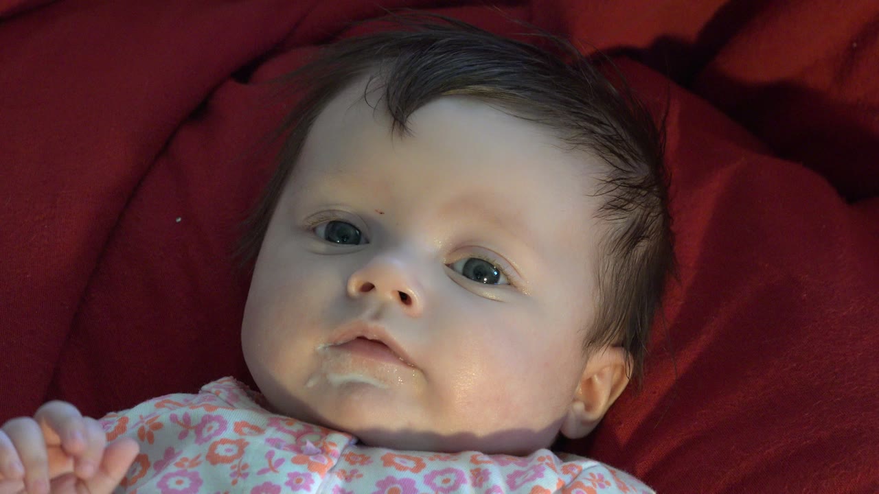 Newborn baby lying on red bedding