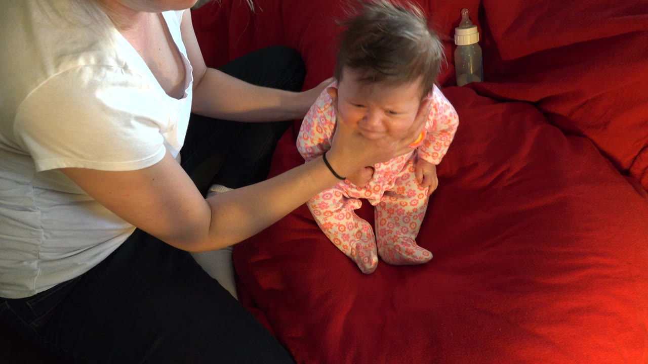 Baby looks forward while adult supports chest.